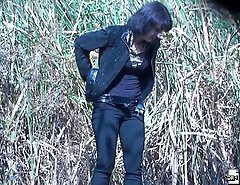 Woman in black pees on trash outdoors