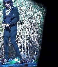 Woman in black pees on trash outdoors