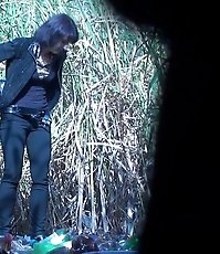 Woman in black pees on trash outdoors