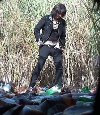 Woman in black pees on trash outdoors