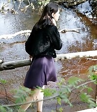 Teenage brunette peeing into a river in the park