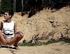 Charming hoochie in glasses pissing into the sand