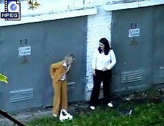 Two pretty office girls pee quietly in a yard