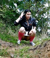 Naughty brunette pisses into a sandpit in forest