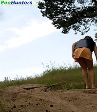 Naughty brunette pisses into a sandpit in forest