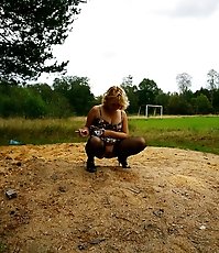 Blonde girl takes a leak in the middle of a field