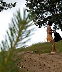 Naughty brunette pisses into a sandpit in forest