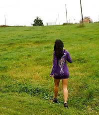 Girl pulls the hem of her dress up to pee outdoors