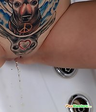 Inked teen makes a golden puddle in the bath tub