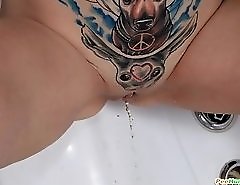 Inked teen makes a golden puddle in the bath tub