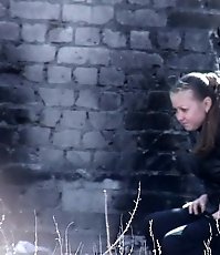 Two girls relieve themselves behind a building